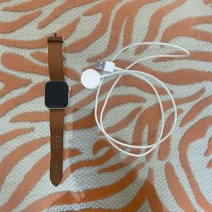 Apple Watch with brown leather band and charger